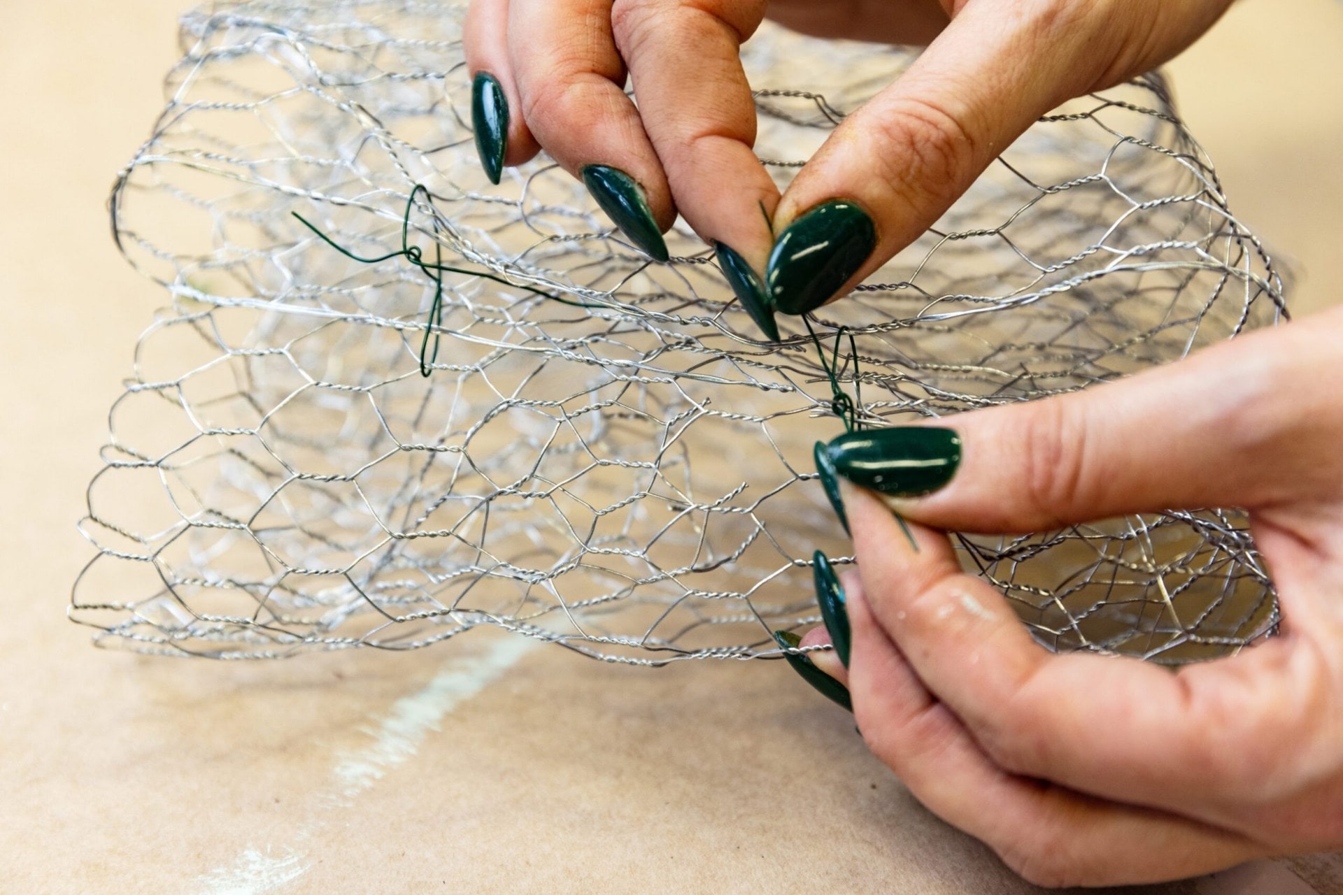 Hands wiring sides of chicken wire together 