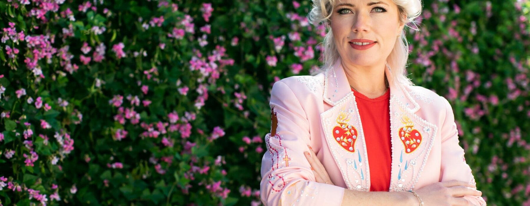 Clementine Ford smiles in front of a hedge.