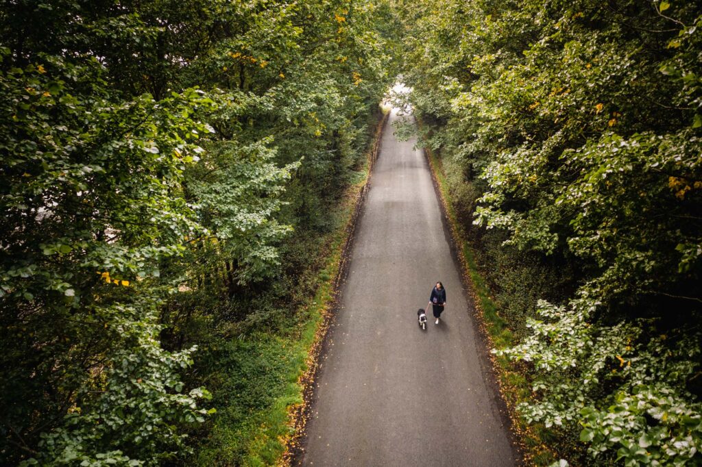 Nikki McIvor and her dog walking down a road lined with trees
