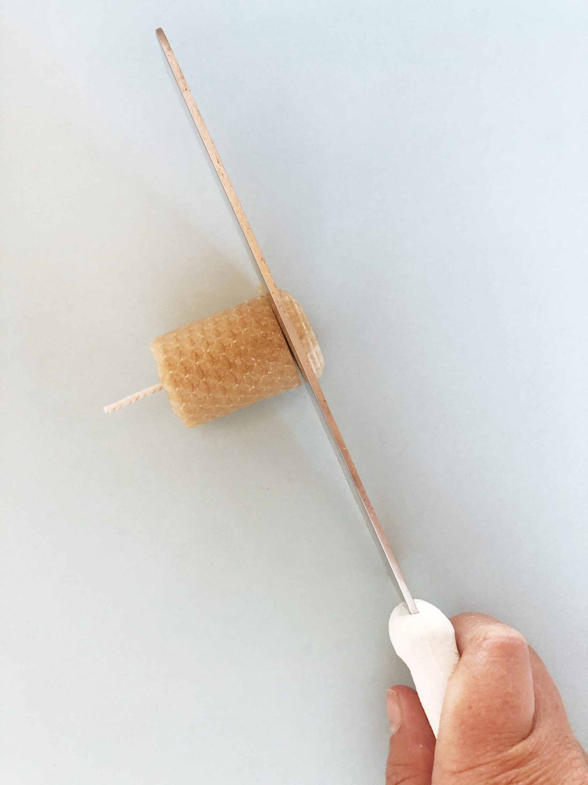 Knife cutting end of bees wax candle