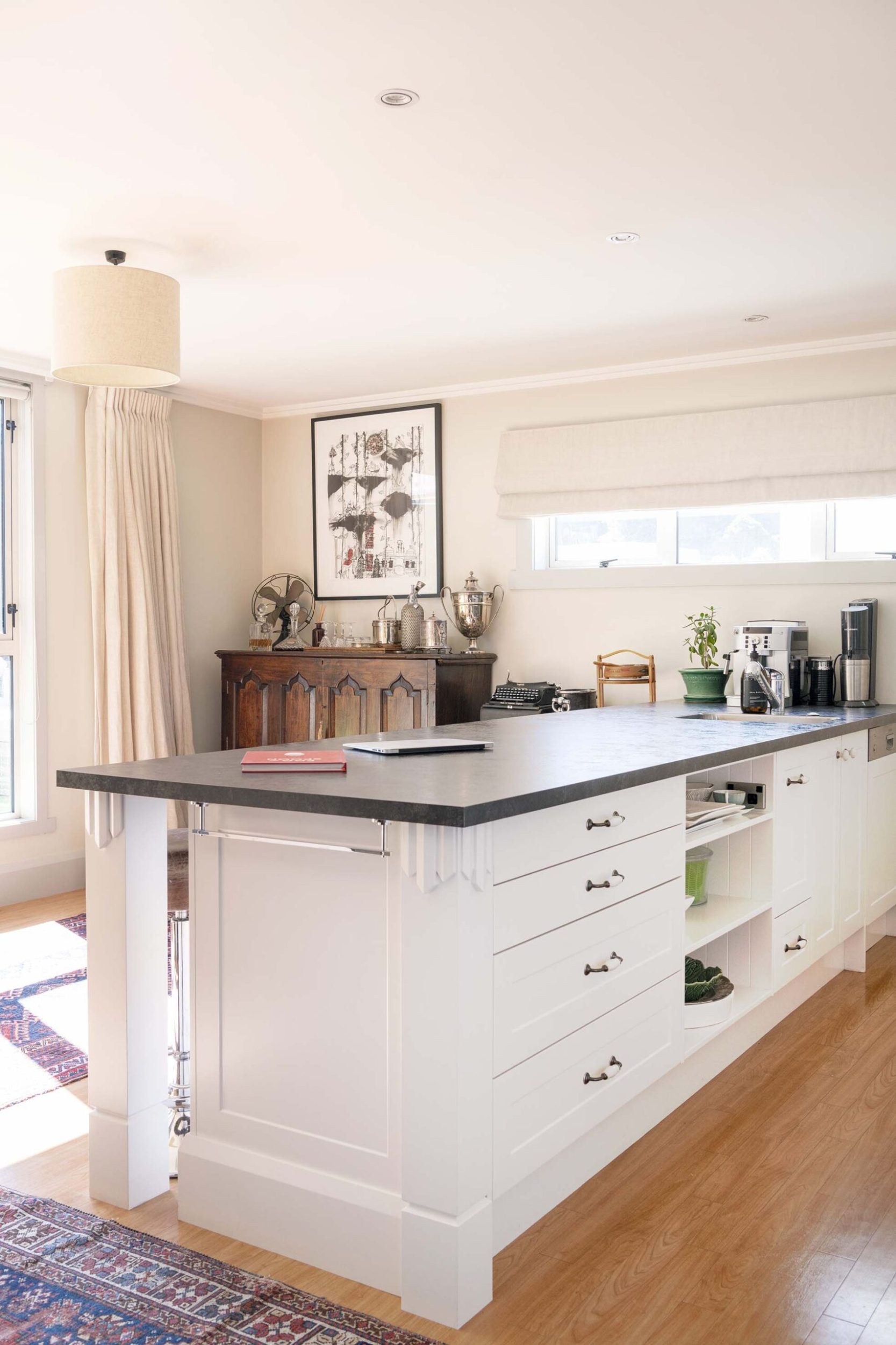 Kitchen with black benchtops, white cabinets and polished wooden floors