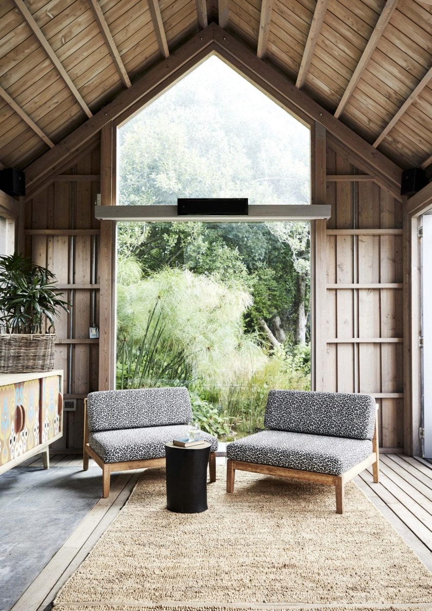 Living room with large tall window facing a green leafy garden 