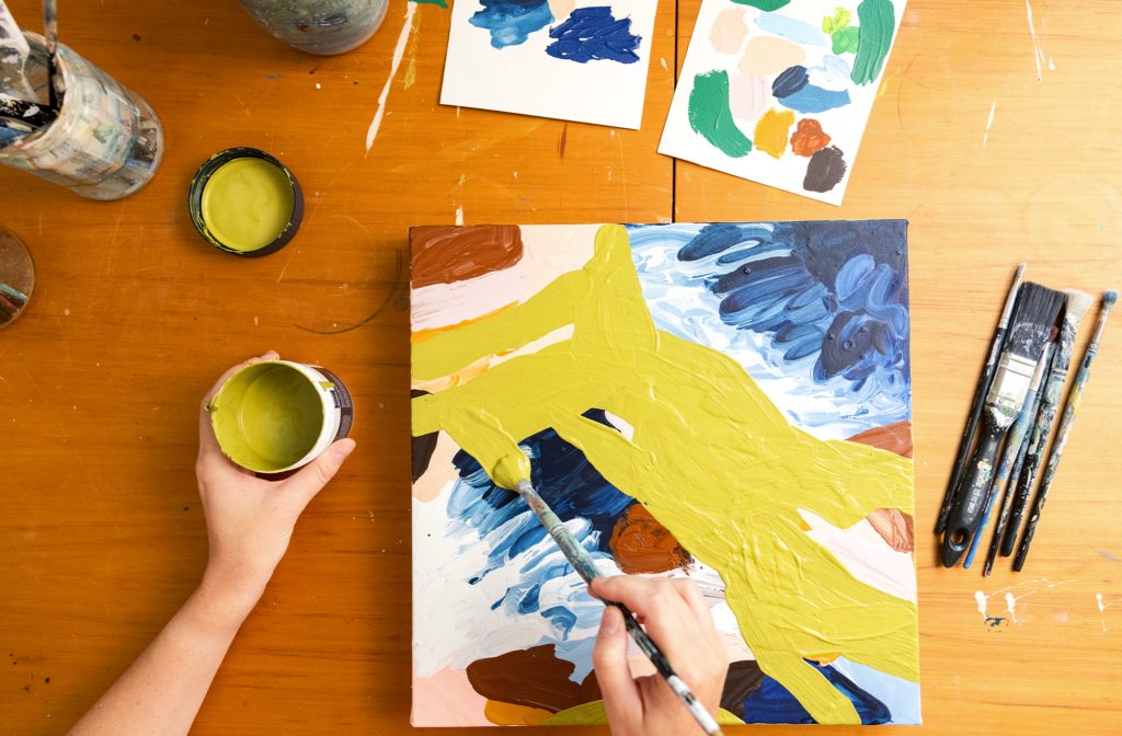 Overhead view of Alice Berry painting art on a square easel