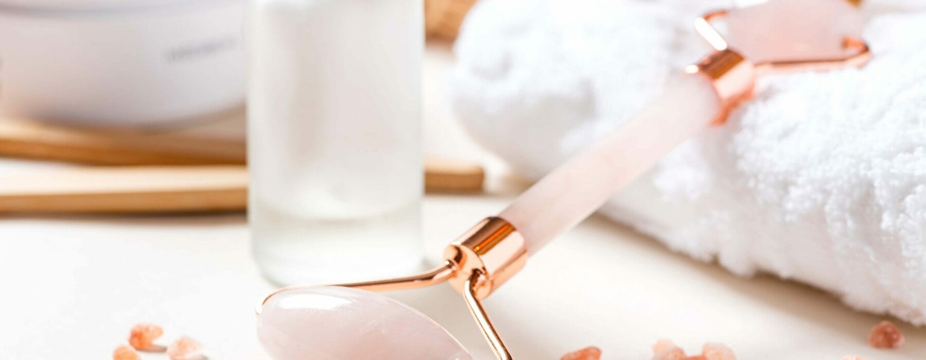 A pink crystal gua sha tool lying on a white towel