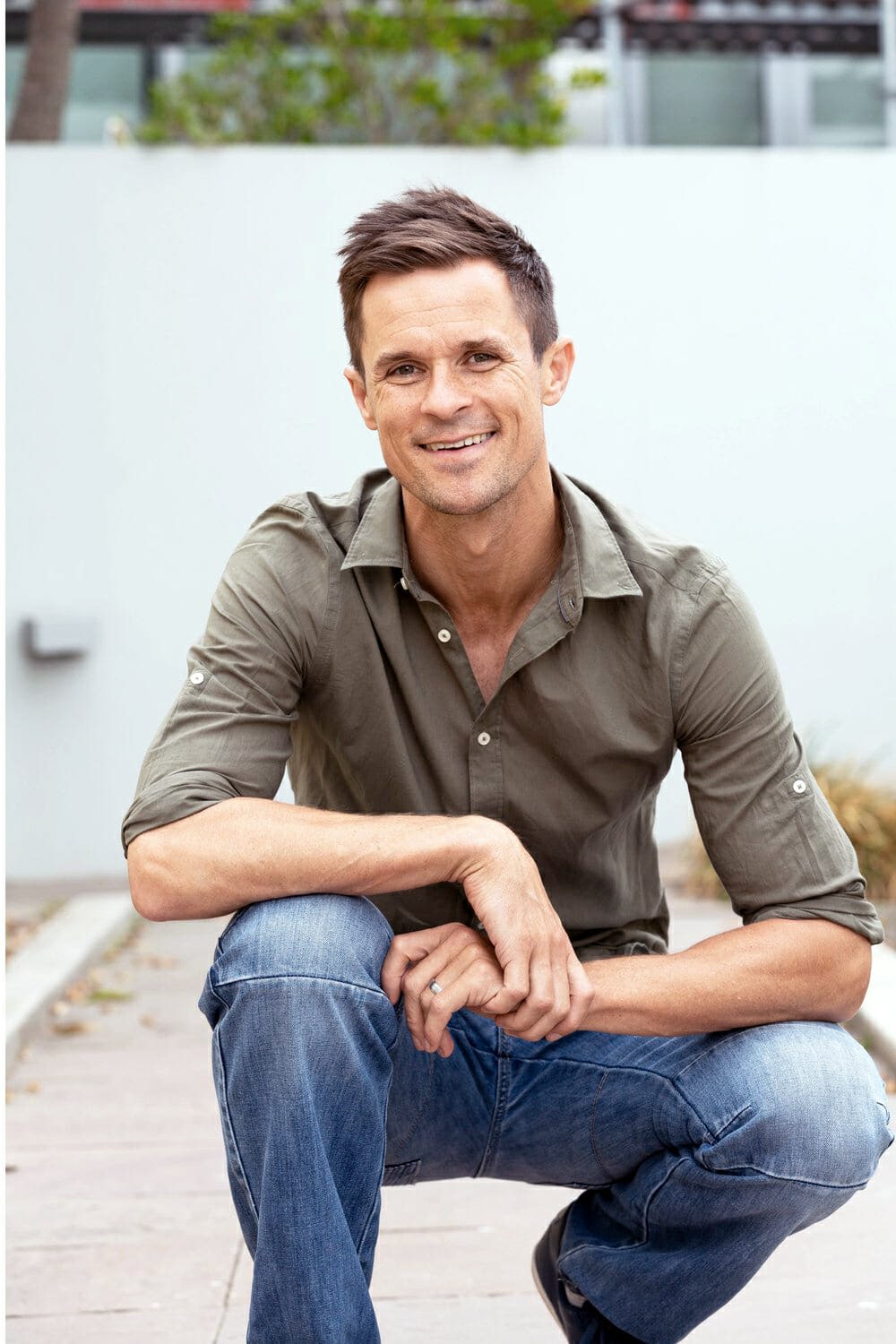 Man crouched down holding his arm. 