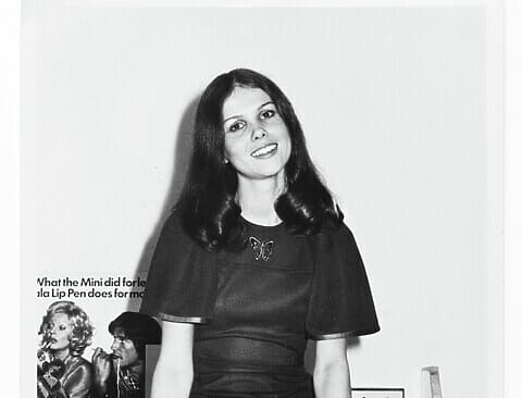 Rowena Roberts sitting on a desk in a black mini dress